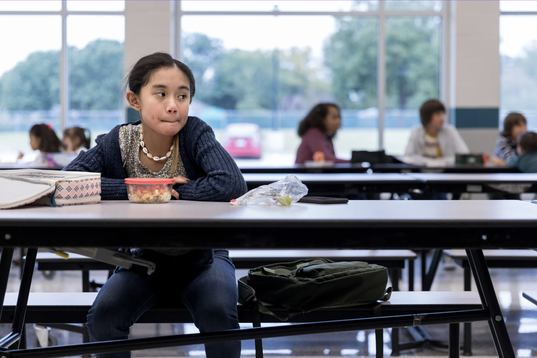 Middle school youth sitting alone at lunch.
