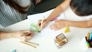 Hands drawing on paper with colored pencils